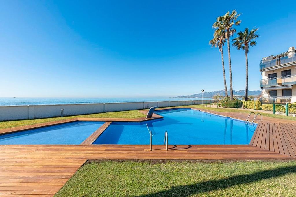 a swimming pool next to the ocean with palm trees at Cambrils seaside luxury solarium in Montroig
