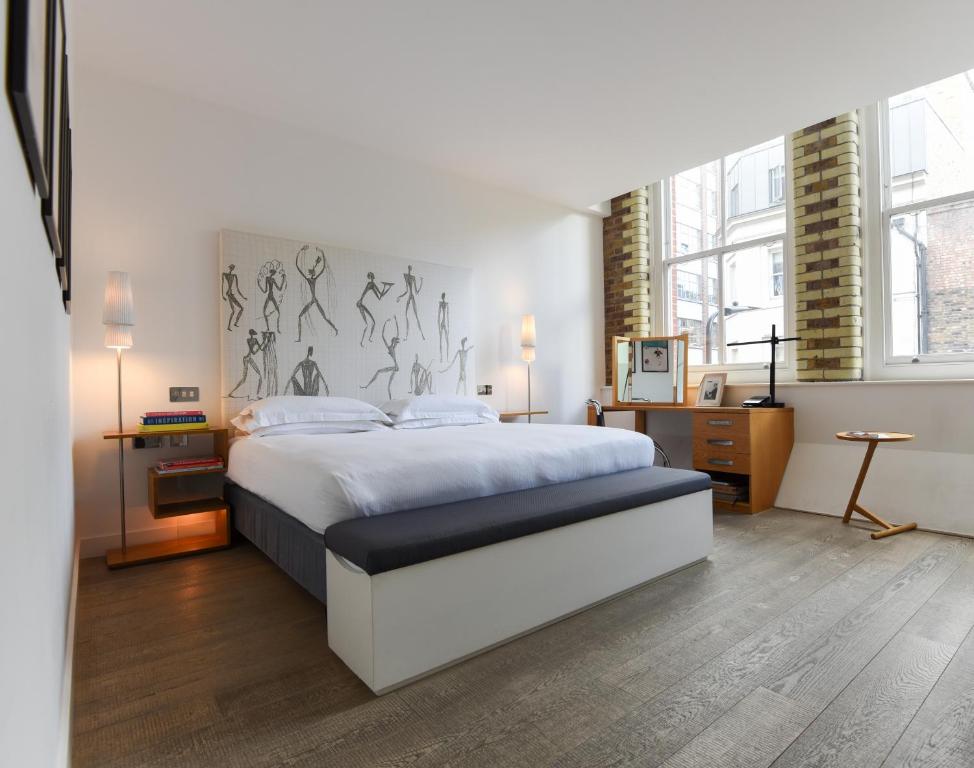 a bedroom with a large white bed and some windows at Boundary Shoreditch in London