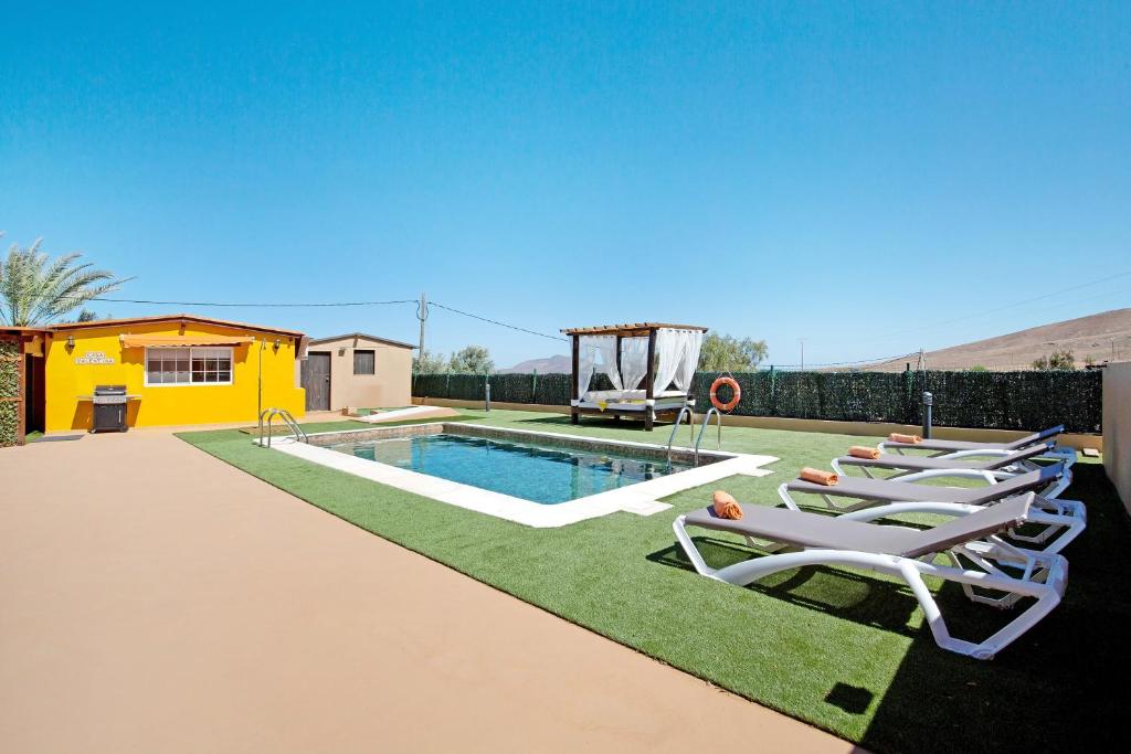 a group of lounge chairs next to a swimming pool at Casa Valentina in Tuineje