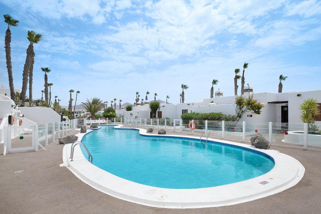a large swimming pool in a resort with palm trees at Puerto Chico E in Playa Blanca