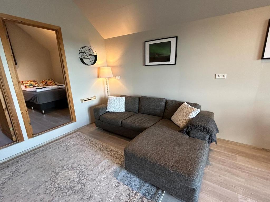 a living room with a couch and a mirror at Mountain View Apartment at Rauðafell in Hvolsvöllur