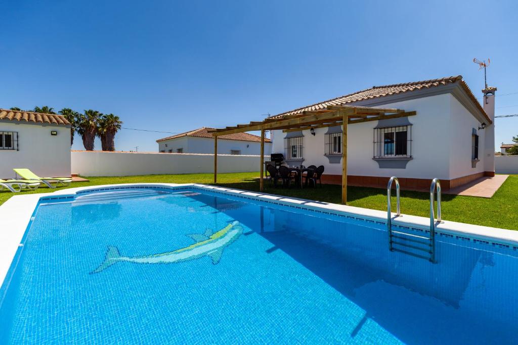a swimming pool in front of a house with a shark on it at Chalet Isla del Sotillo in Chiclana de la Frontera