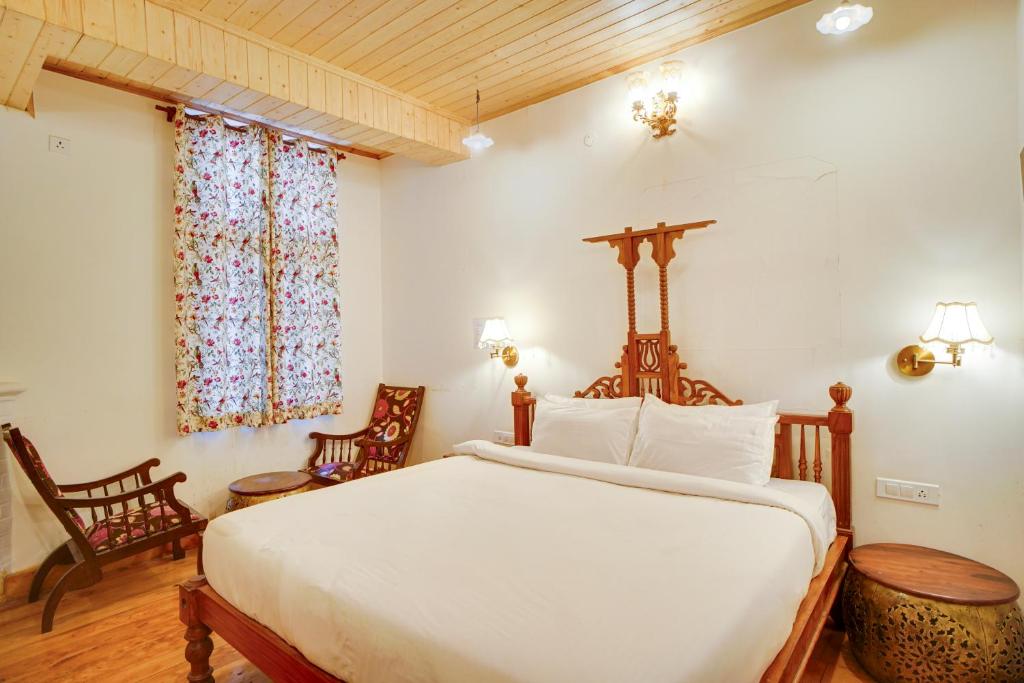 a bedroom with a large bed and two chairs at Danish Villa Heritage Property in Shimla