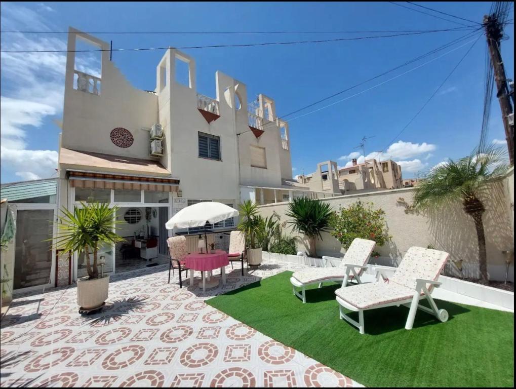 a patio with chairs and a lawn in front of a building at R-15 Large Holiday House in Torrevieja
