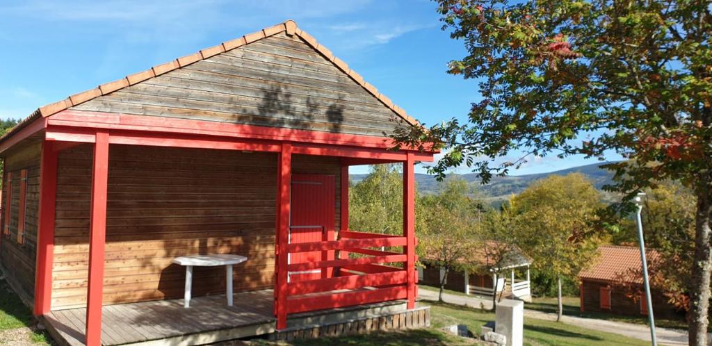 a small cabin with a red door and a table on a deck at 16 Chalet Hibiscus in Blavignac