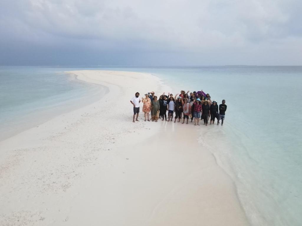 a group of people standing in the water on a beach at The Sandora Villa in Biladu