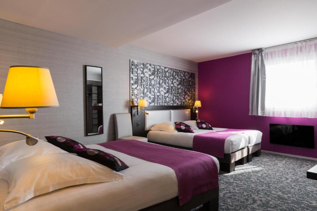 two beds in a hotel room with purple walls at Relais St Eloi, Sure Hotel Collection by Best Western in Tours