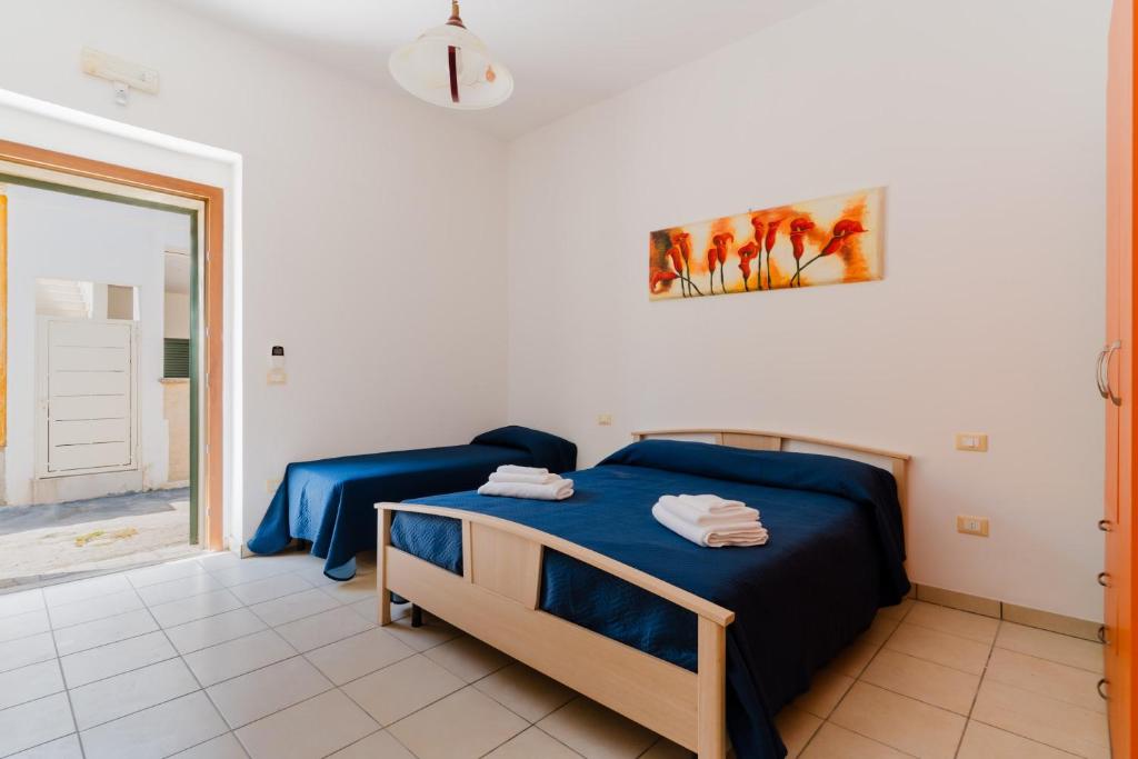 a bedroom with a bed with blue sheets and a window at La casetta 462 in Torre San Giovanni Ugento