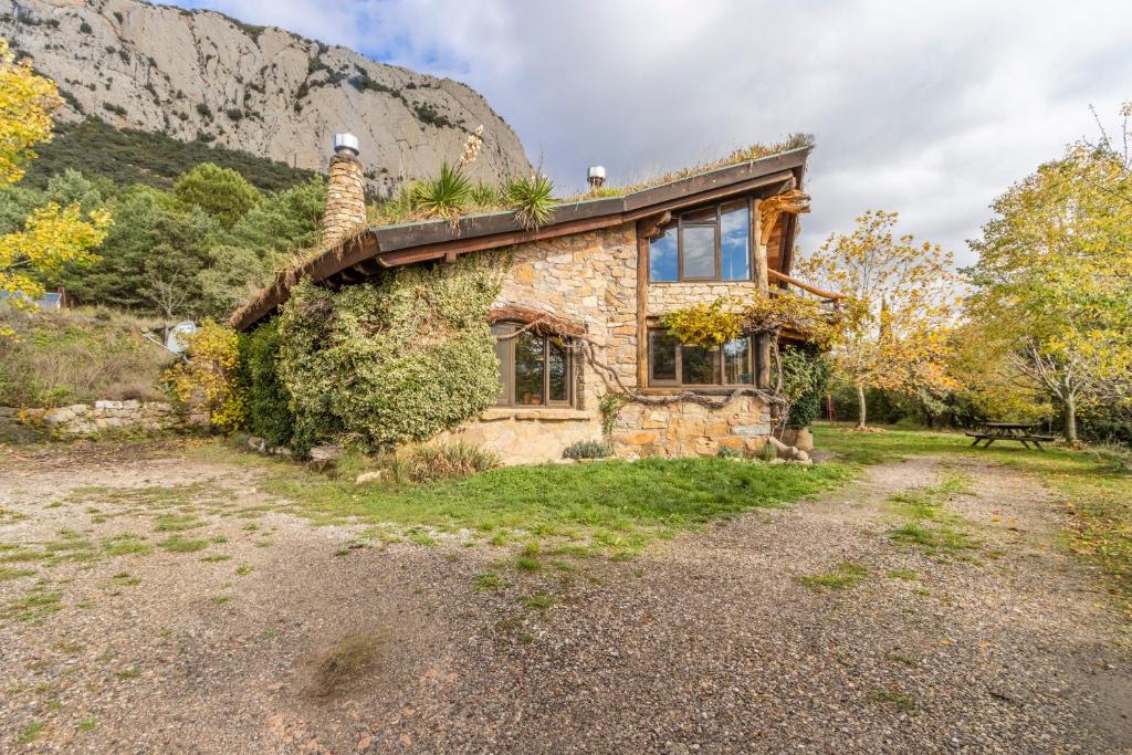 ein altes Steinhaus mit einem Berg im Hintergrund in der Unterkunft Cal Serrat in Abella de la Conca
