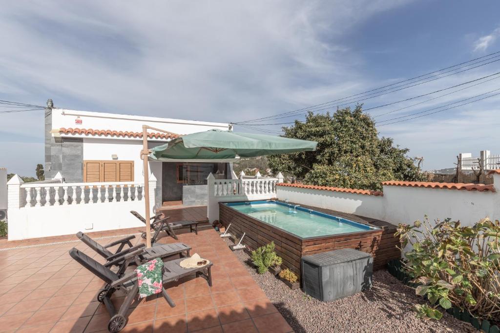 a house with a swimming pool and an umbrella at Teror Hills in Teror
