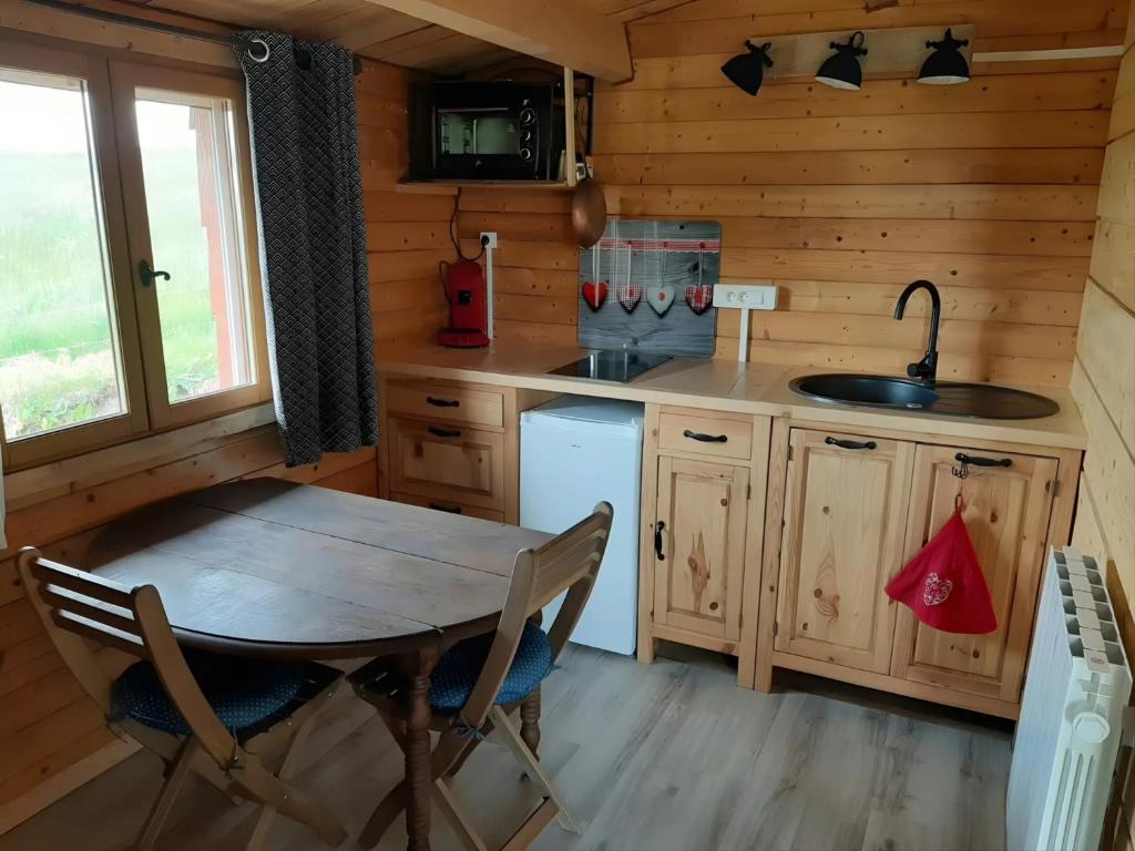 a kitchen with a table and a sink in a cabin at Gîte à la ferme- Chalet à la nuitée in Mazan-lʼAbbaye