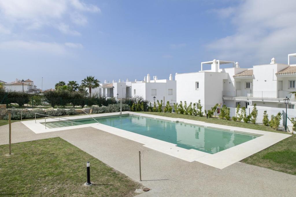 a swimming pool in front of a white building at Moderno Apartamento Atlanterra in Zahara de los Atunes