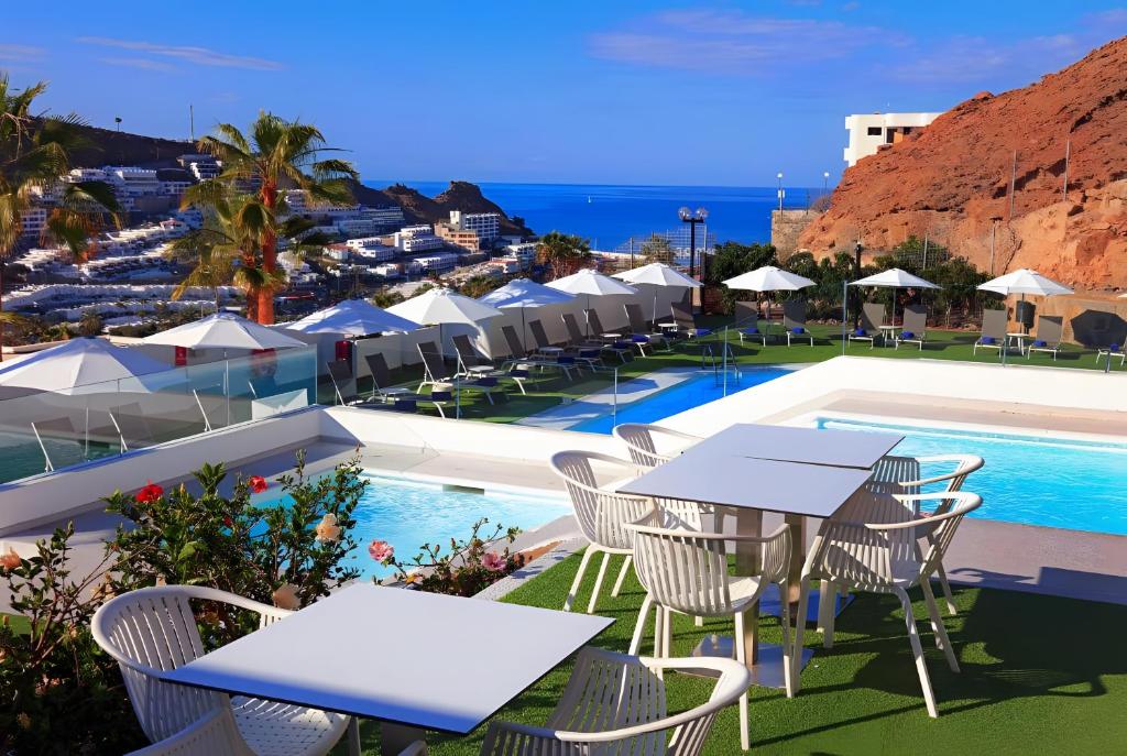 a hotel with tables and chairs next to a pool at Canaima 223 - Puerto Rico in Puerto Rico de Gran Canaria