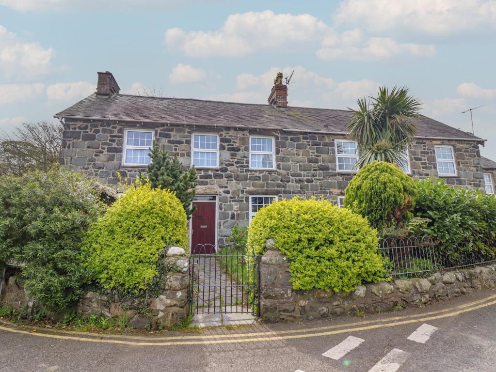 a stone house with a fence in front of it at Glanrafon in Llwyngwril