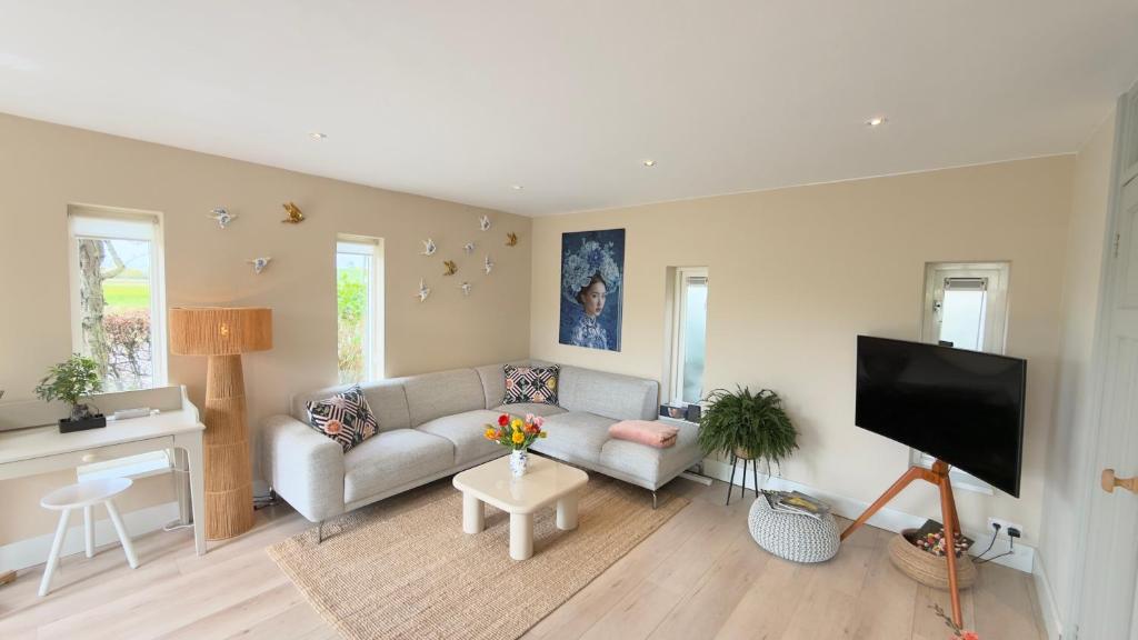 a living room with a couch and a flat screen tv at Tulipa Near Beach & Dunes with Free Parking in Noordwijkerhout