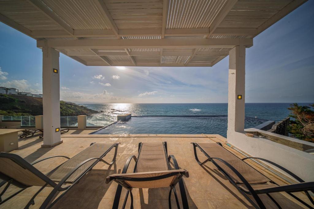 a porch with chairs and a view of the ocean at Villa Pantheon with Private Pool & Jacuzzi in Pomos