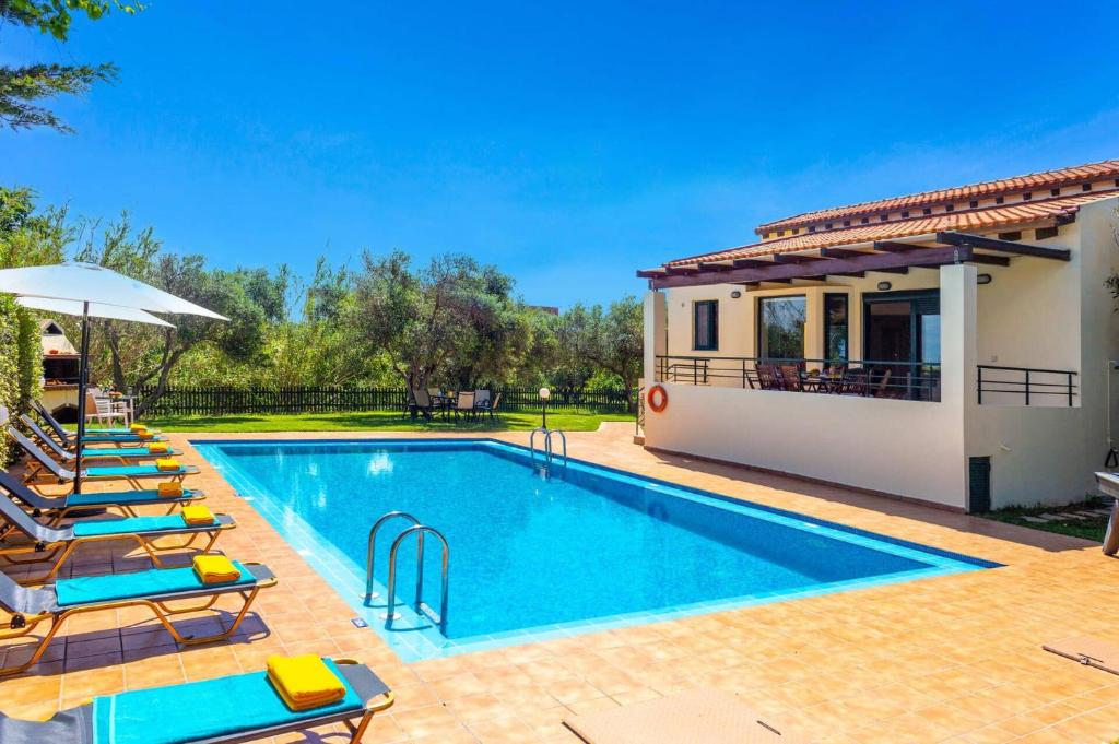 a swimming pool with lounge chairs and a house at Villa Anna Maria by Villa Plus in Pírgos Psilonérou