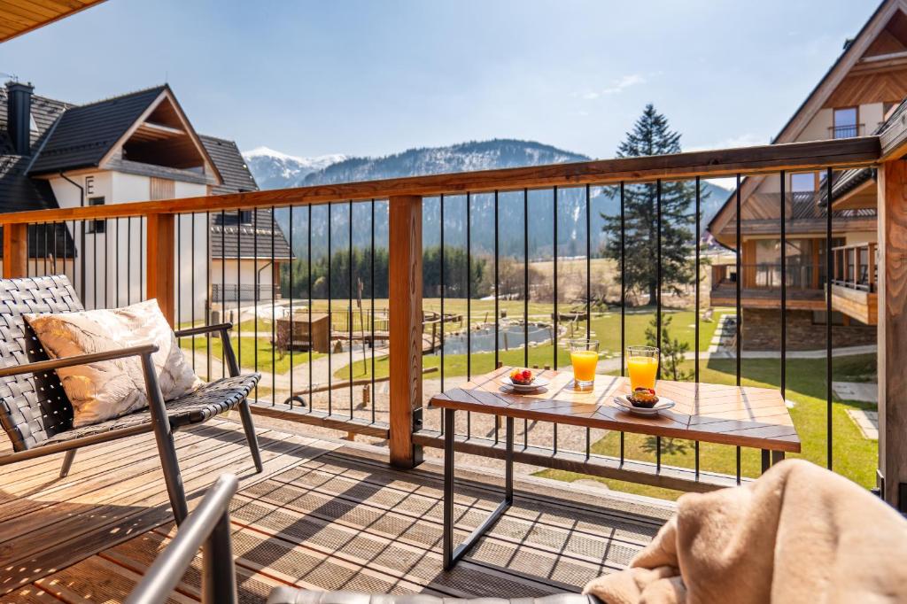 a balcony with a table and two glasses of orange juice at Mountain Mood by Apart Concept Podhale in Kościelisko
