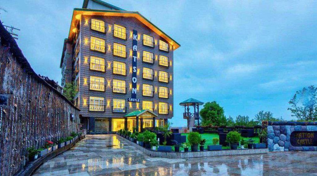 a large building with lights on in the evening at Hotel Katson Castle with Sunset View Dharamshala in Dharamshala
