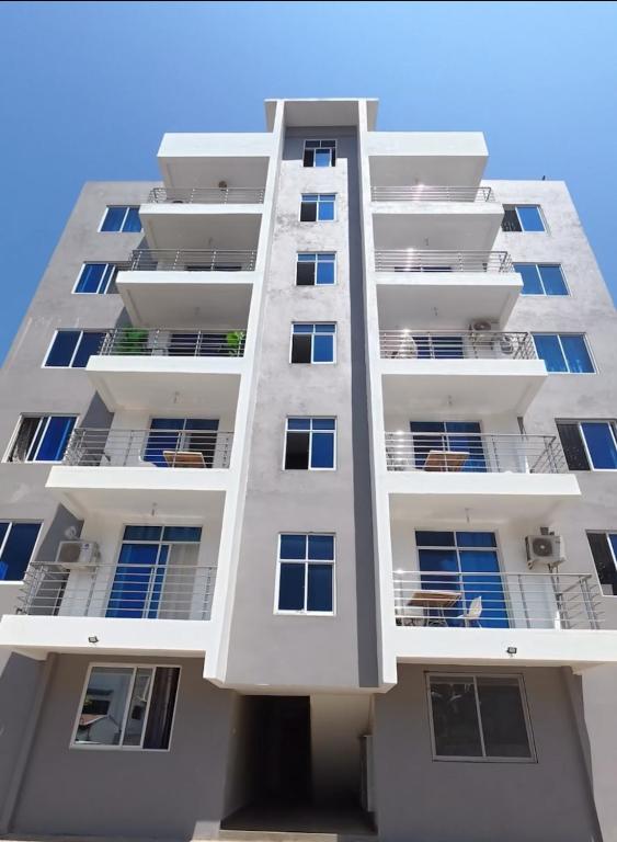 a tall white apartment building with balconies at Auryhomes in Mombasa