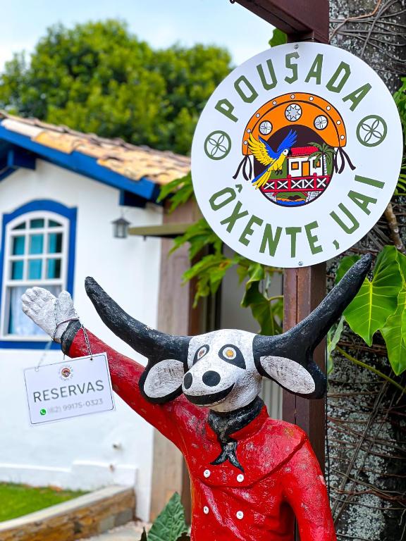 a sign for a restaurant with a statue of a cow at Pousada Oxente Uai! in Pirenópolis