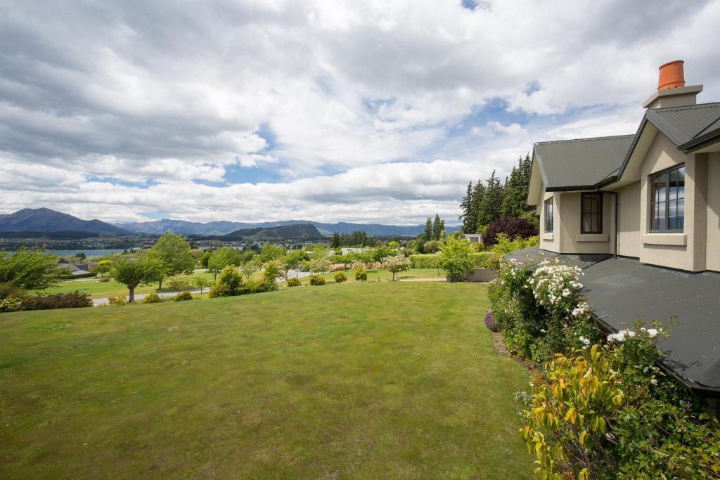 a house with a large yard with a green lawn at Beautiful Seasons in Wanaka