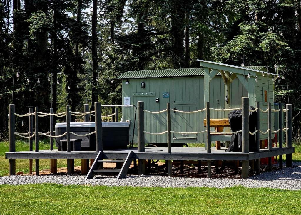 a playground with two benches in front of a building at Firbank Park Shepherd Huts in Dinnet