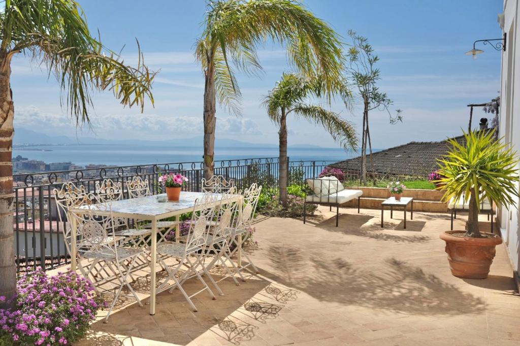 a patio with a table and chairs and palm trees at Villa Ipomea - Terra Suite in Salerno