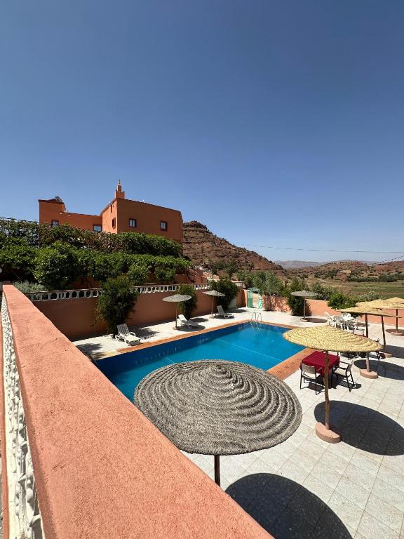 a swimming pool with tables and umbrellas on a building at Green Valley Lodge - Atlas Mountains Nature in Taroudant