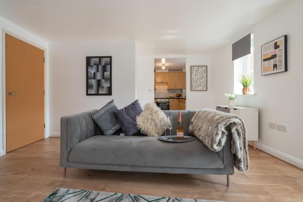a living room with a gray couch and a kitchen at Stylish 2-Bed Manning Gardens in South Norwood