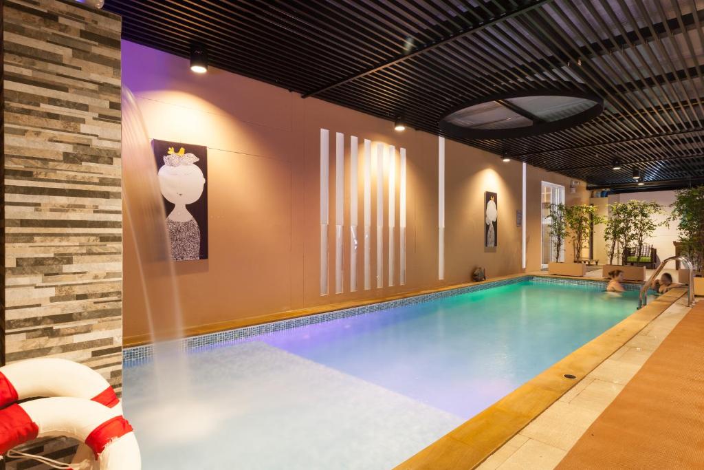 An indoor swimming pool with a tiled deck and warm decorative lighting.