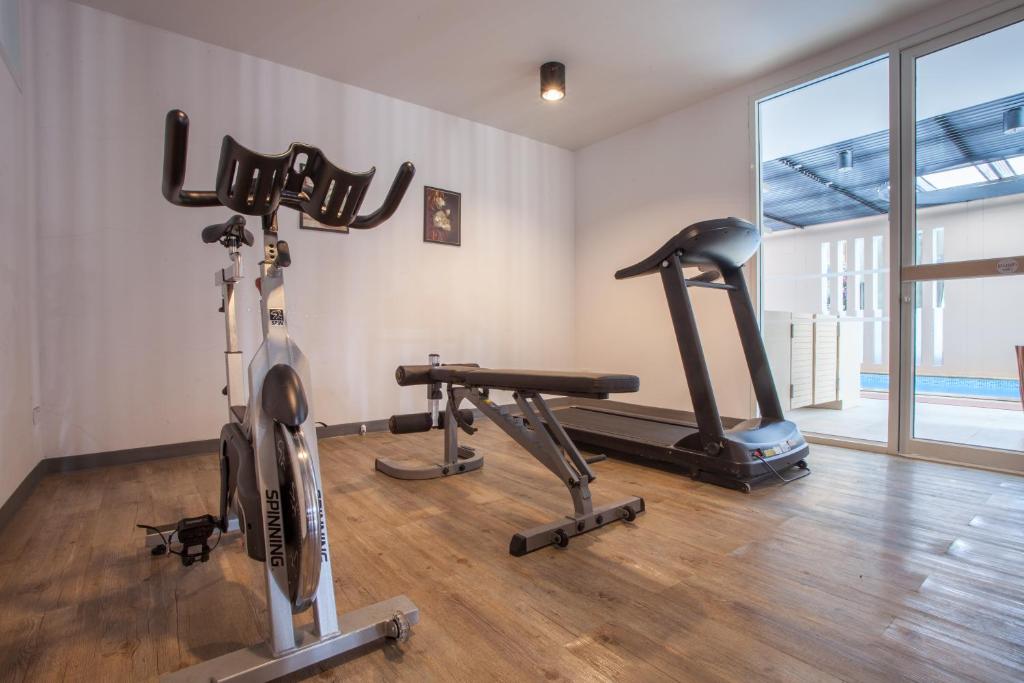 A compact fitness room with cardio equipment and a weight bench beside pool-facing glass.
