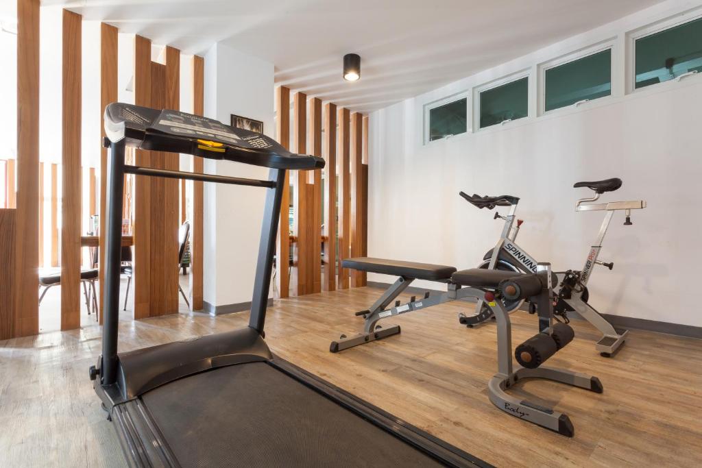 A bright fitness room with a treadmill, two exercise bikes and a weight bench.