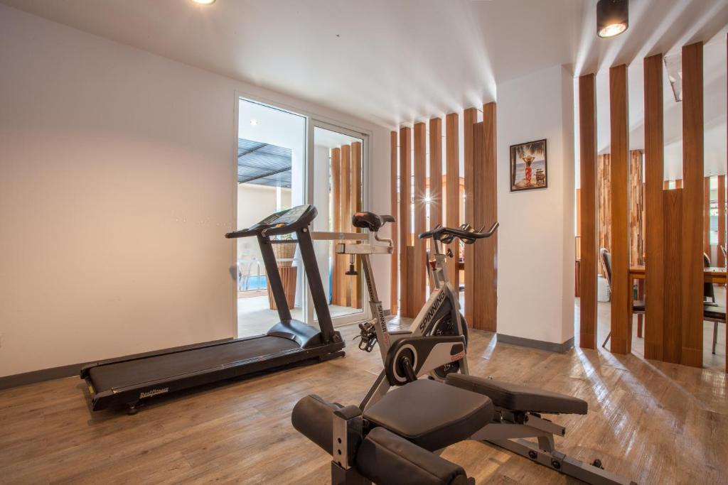 A compact gym arranged with cardio machines, a weight bench and mirrored wood-slat walls.