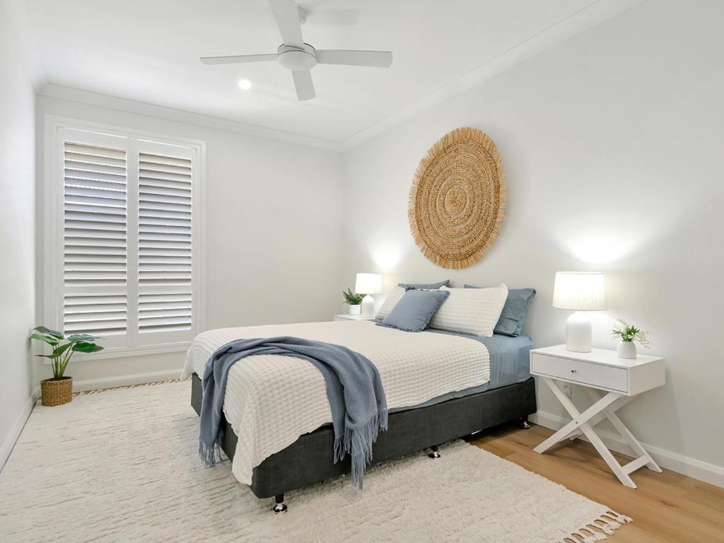 a white bedroom with a bed and a window at Lillian Waters Retreat in Yamba
