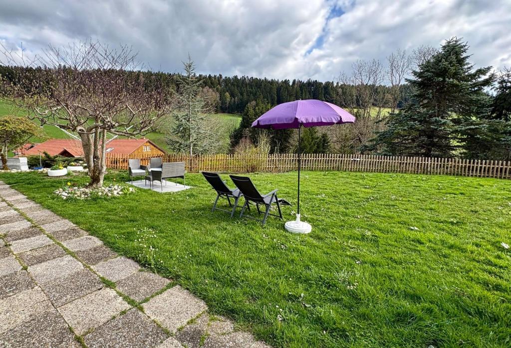 a purple umbrella in a yard with chairs and a table at Appartement le Refuge du Cerisier in La Chaux-de-Fonds