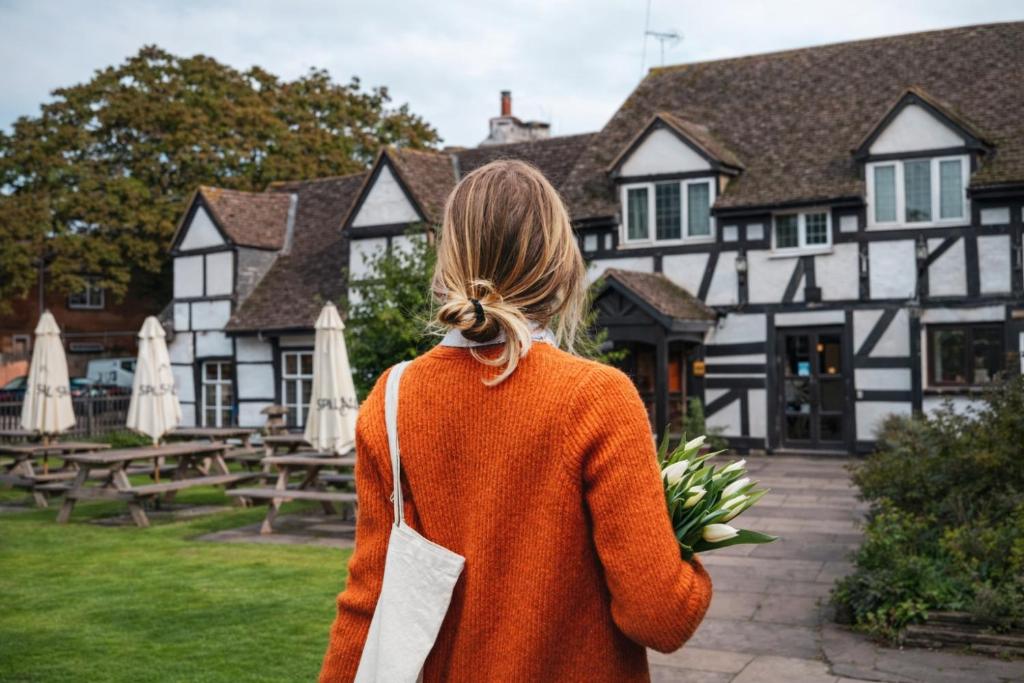 a woman walking in front of a black and white building at The Thatch Inn in Gloucester