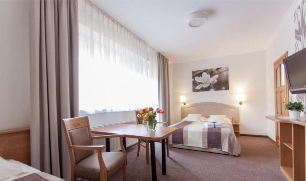 a hotel room with a table and a bed at Villa Anna - Noclegi Rooms - FREE parking, taras, 1500m do Starówki in Gdańsk