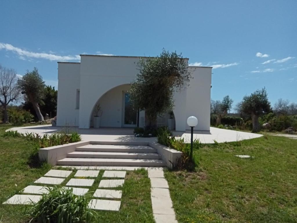 a white building with a pathway in the grass at Villa Bello camere in Giurdignano
