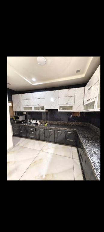a kitchen with white cabinets and a marble floor at Rudra BNBF in Gandhidham