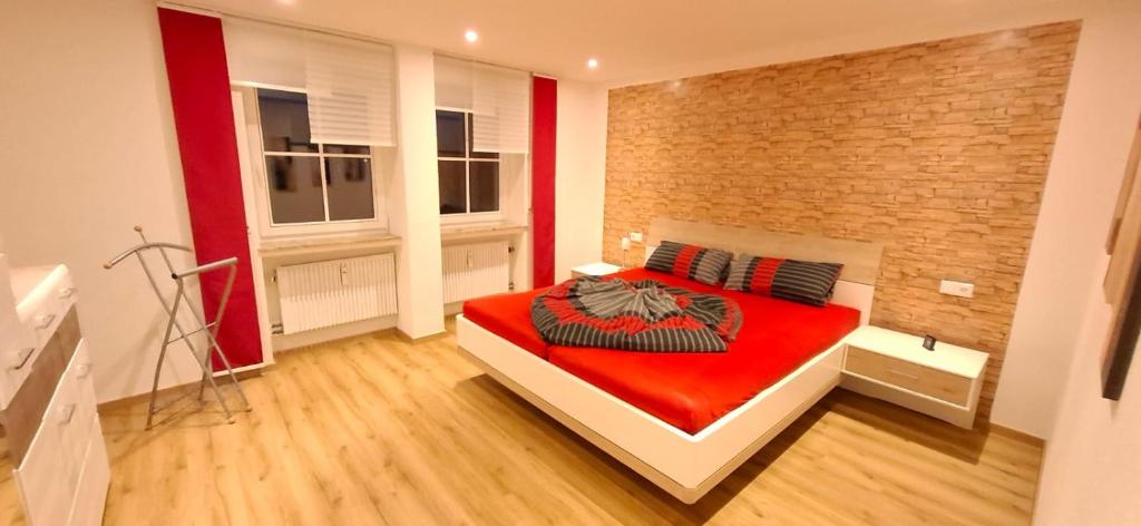 a bedroom with a red bed and a brick wall at Ferienwohnung zum Albuch in Nördlingen