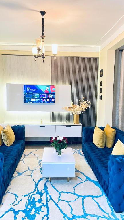 a living room with blue couches and a tv at Modest Spacious Apartment in Kampala