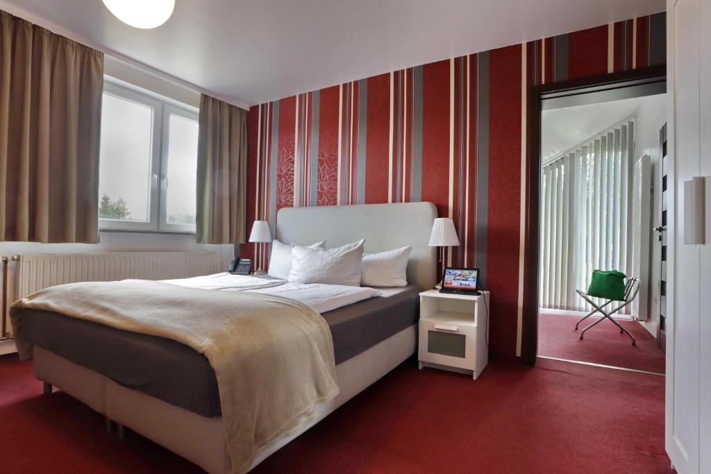a bedroom with a large bed with red walls at VITALHOTEL Schulenberg in Schulenberg im Oberharz