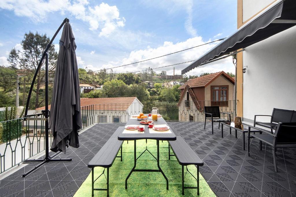 a patio with a table and an umbrella on a balcony at Casa da Ponte in Lombinha