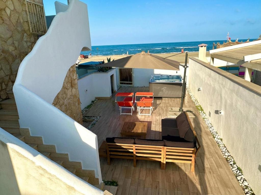 a balcony with a bench and an umbrella and the beach at Fiorucci Apartments - Veronica's House Fiumicino in Focene