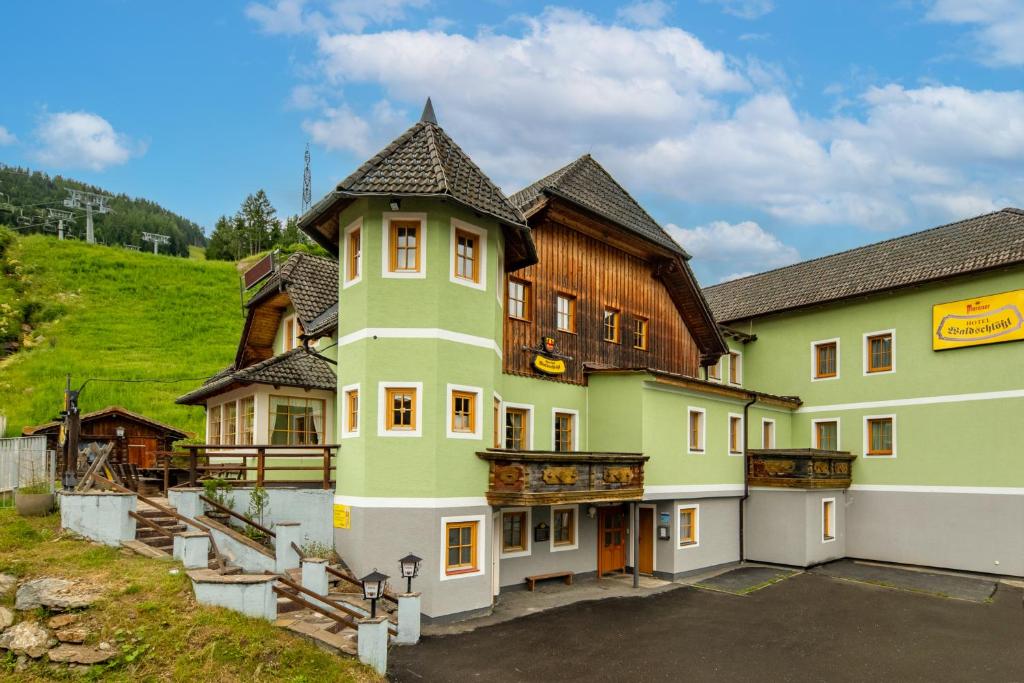 a large green building with a wooden roof at Waldschlössl Gasthof in Sankt Lorenzen ob Murau
