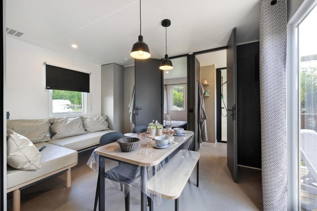 a living room with a table and a couch at Mobilehome riviera avec terrasse 48 in Saint-Gervais