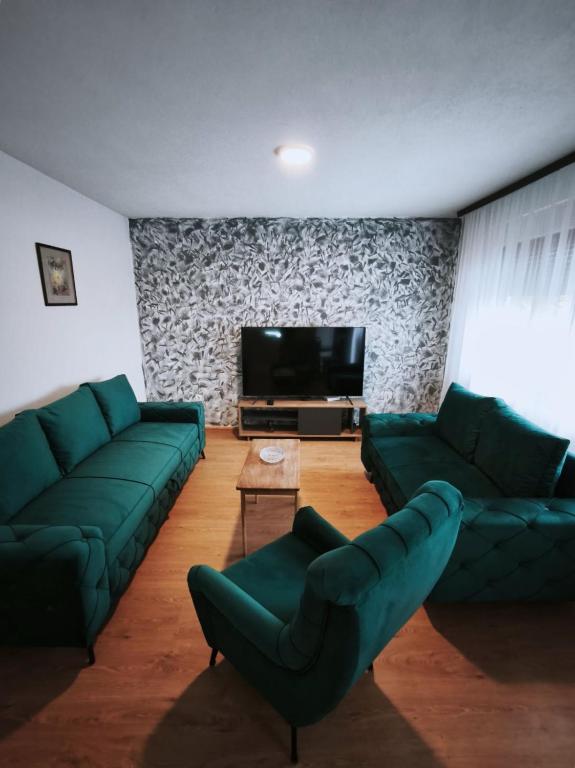 a living room with green couches and a flat screen tv at Lavanda Lux in Drvar