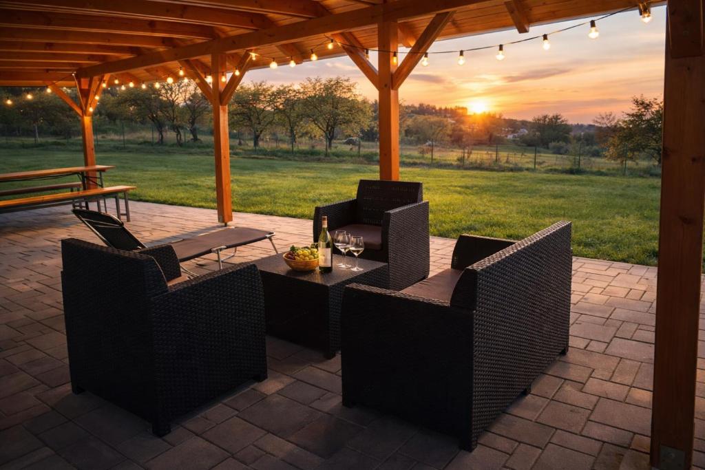a patio with a table and chairs with a sunset in the background at Sódomb vendégház in Egerszalók