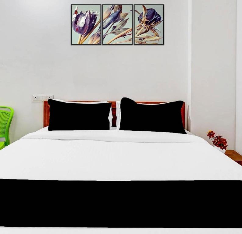 a white bed with black pillows in a bedroom at Shivam Elite Comforts in Bangalore